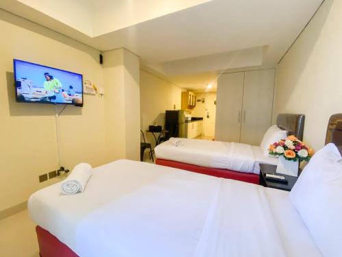 三宝垄Minimalist Studio Room Marquis de Lafayette Apartment By Travelio的一间配有两张床和一台平板电视的酒店房间