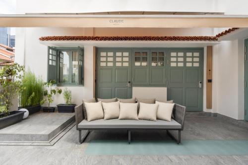 a porch with a couch in front of a green door at Claude Hotel in Singapore