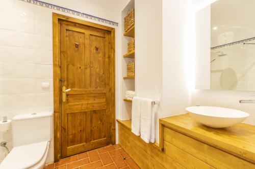 a bathroom with a wooden door and a sink at Cal Comorera in Masoteras