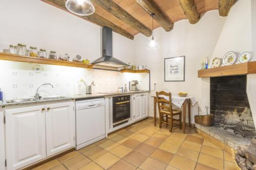 a kitchen with white cabinets and a fireplace at Cal Comorera in Masoteras