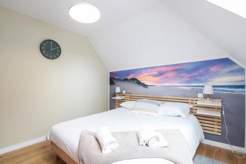 a bedroom with a large white bed with a painting on the wall at Aquagîte - Terrasse - Parking - Proche plage in Baden