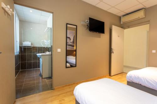 a hotel room with two beds and a bathroom at Logis Hôtels et restaurant La Pause Rn7 in La Coucourde