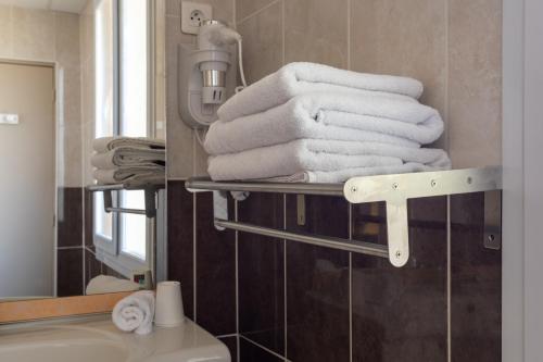 a pile of towels on a towel rack in a bathroom at Logis Hôtels et restaurant La Pause Rn7 in La Coucourde