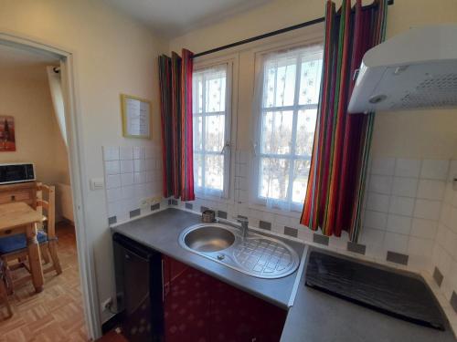 a small kitchen with a sink and two windows at Appartement proche Thermes Saint Roch avec wifi et animaux admis - FR-1-541-134 in La Roche-Posay