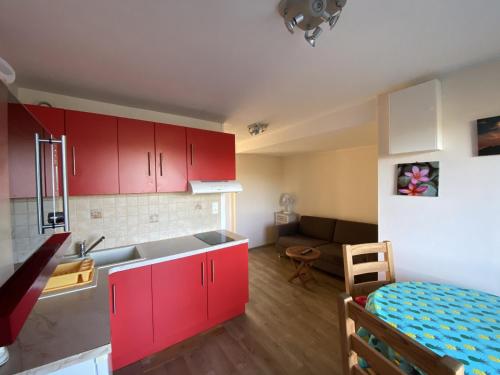 une cuisine avec des placards rouges et un salon dans l'établissement T2 avec terrasse et Wi-Fi, proche des Thermes du Connétable - FR-1-541-123, à La Roche-Posay