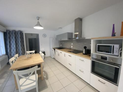 une cuisine avec une table en bois et un micro-ondes dans l'établissement Maison rénovée avec cuisine équipée à La Roche-Posay - FR-1-541-148, à La Roche-Posay