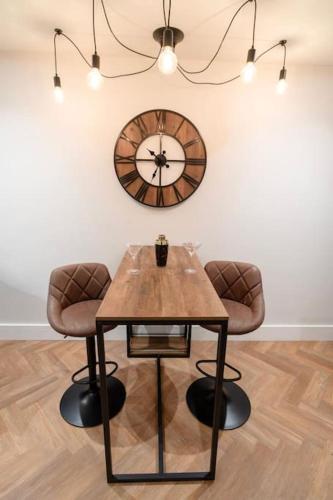 a table with two chairs and a clock on the wall at Hidden Home in Haywards Heath
