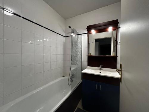 une salle de bain avec un lavabo, une baignoire et un miroir dans l'établissement Appartement Résidence, Piscine, 200m des Thermes - FR-1-541-149, à La Roche-Posay