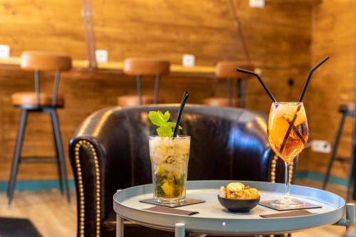 two cocktails sitting on a table in a restaurant at Logis Hôtels et restaurant La Pause Rn7 in La Coucourde