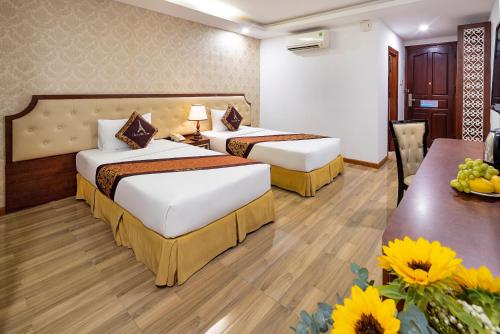 a hotel room with two beds and a table at Paris Luxury Hotel & Apartment Nha Trang in Nha Trang