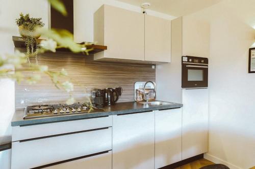 a kitchen with white cabinets and a stove at Grijze Veen 8-person bungalow in Voorthuizen