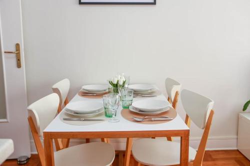 a dining room table with white plates and chairs at Cosy 3 pièces à 5 min de la PROM in Nice