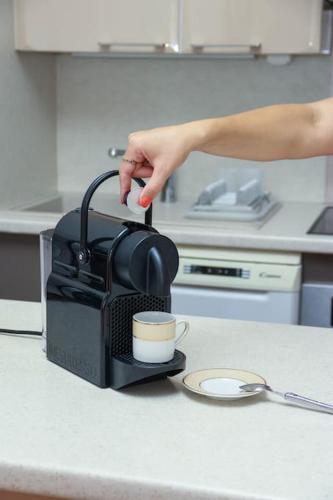 a person is holding a cup in a coffee maker at Cosy 3 pièces à 5 min de la PROM in Nice