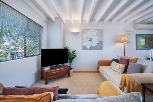 a living room with a couch and a flat screen tv at Clarence Corner - Contemporary meets Cottage Style in Brisbane