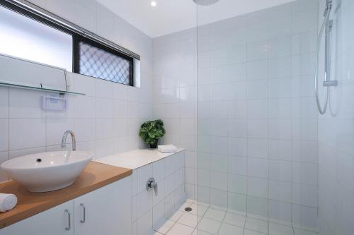 a white bathroom with a sink and a shower at Clarence Corner - Contemporary meets Cottage Style in Brisbane
