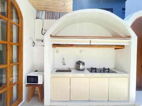 a small kitchen with a stove and a microwave at La Rylin Villa in Kuta