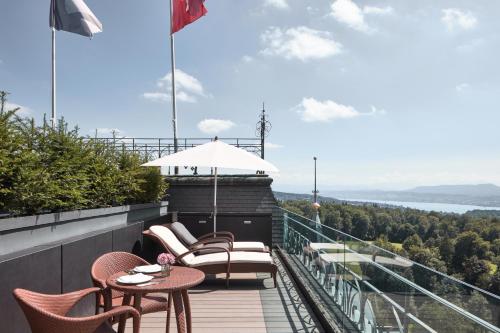 a balcony with chairs and tables and an umbrella at The Dolder Grand - City and Spa Resort Zurich in Zürich