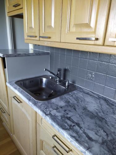 a kitchen counter with a sink and wooden cabinets at Kaukajärven Joutsen - valoisa ja tilava kaksio in Tampere