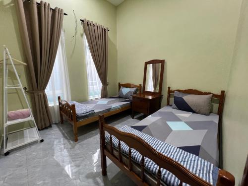 a bedroom with two beds and a mirror at Robi Homestay in Alor Setar