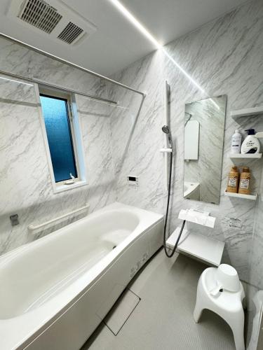 a white bathroom with a tub and a toilet at Akikawa Koshi 9 プレミアム鉄骨 一棟貸切ヴィラ in Yuge