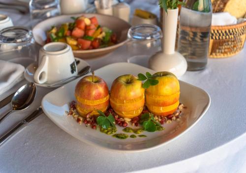 a plate with apples and pomegranates on a table at Gorilla Heights Lodge by NEWMARK in Kisoro