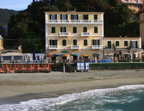 a building on the beach with chairs and umbrellas at Hotel Baia in Monterosso al Mare