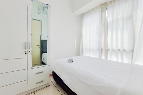 タンゲランにあるSimple and Comfort Design 2BR Apartment at M Town Residence By Travelioのベッドと鏡のある白い寝室