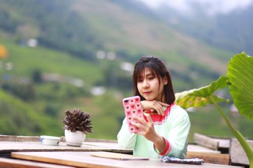 a woman sitting at a table looking at her cell phone at Boutique En Hotel Sapa in Sa Pa