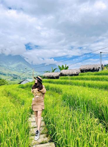 a woman walking down a path through a field at Boutique En Hotel Sapa in Sa Pa