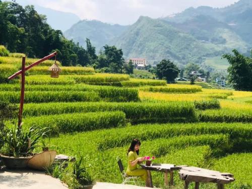 a woman sitting at a table in front of a field at Boutique En Hotel Sapa in Sa Pa
