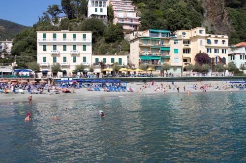 a group of people swimming in the water at a beach at Hotel Baia in Monterosso al Mare