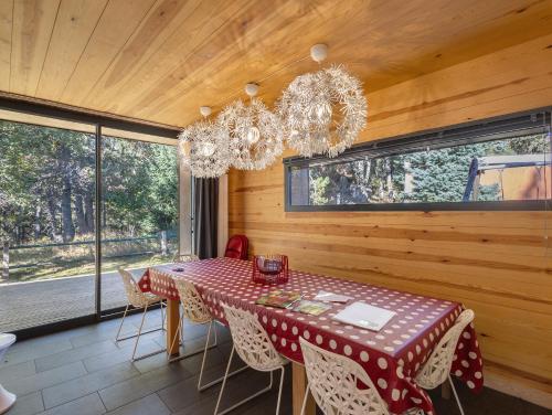 une salle à manger avec une table, des chaises et des fenêtres dans l'établissement Magnifique Chalet Moderne Familial, à Font-Romeu-Odeillo-Via