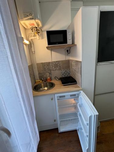 une petite cuisine avec un évier et un micro-ondes dans l'établissement Studio 300m de la plage, au Havre