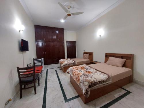 a bedroom with two beds and a chair and a fan at City Home Guest House F8-3 in Islamabad