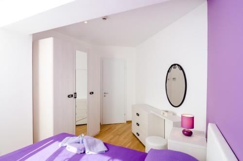 a white and purple bedroom with a purple bed and a mirror at Apartment Atlant in Dubrovnik