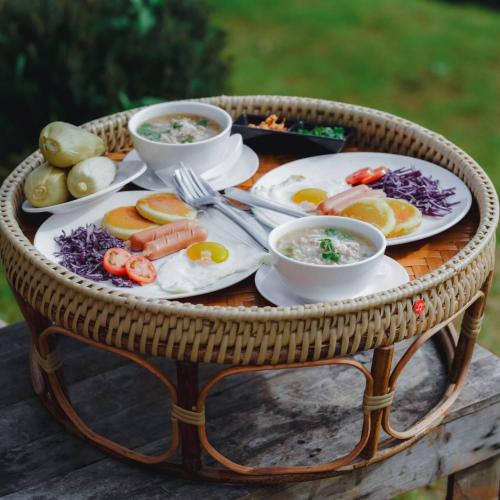 a wicker table with plates of food on it at ตั้วบ้านดิน Tuabaandin in Ban Thung Phan Ha