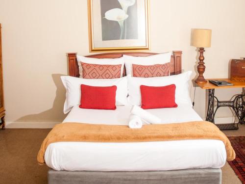 a bedroom with a large bed with two red pillows at Hudson Haven Bed & Breakfast in Pietermaritzburg