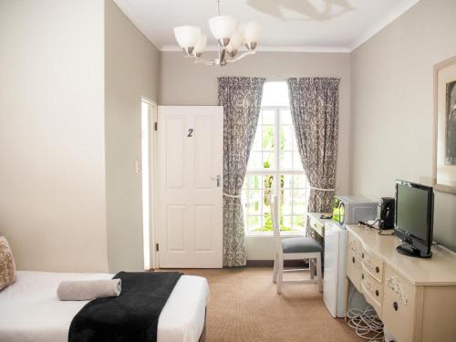 a bedroom with a bed and a tv and a window at Hudson Haven Bed & Breakfast in Pietermaritzburg