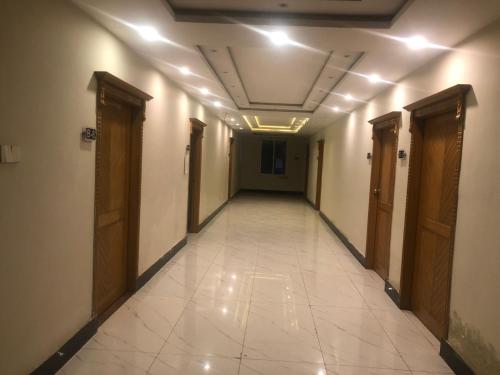 einen leeren Flur mit Türen und Fliesenboden in der Unterkunft Al Buraq Hotel in Islamabad