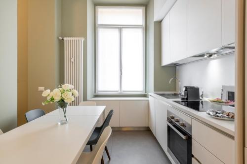 a kitchen with a table with a vase of flowers on it at Milan Royal Suites - Centro in Milan