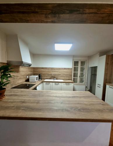 une cuisine avec un grand comptoir en bois dans l'établissement Chaleureux moulin en pierre avec maison attenante, à Castérat-Bouzet