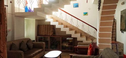 a living room with a staircase and a couch at Alor Niloy in Purulia