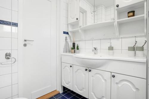 a white bathroom with a sink and a shower at Fresh og moderne leilighet med 3 soverom på Jeløy in Moss