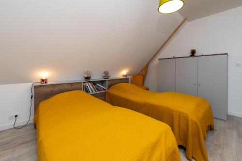 two beds in a room with yellow sheets at Maison bord de mer in Sarzeau