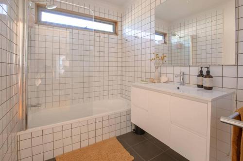 un bagno piastrellato bianco con vasca e lavandino di Little Possum Shack waterfront cottage a Port Arthur