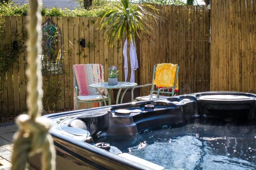 a hot tub in a backyard with a table and chairs at Kionslieu Farm Cottages in Foxdale