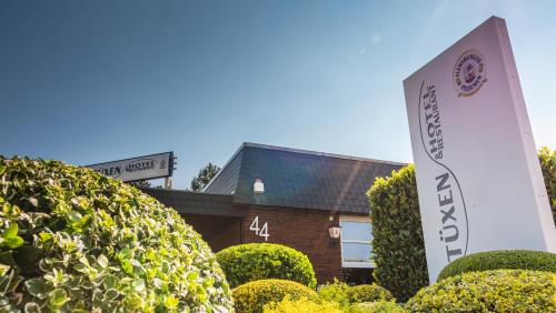 a sign in front of a building with bushes at Hotel-Restaurant Tüxen in Rendsburg