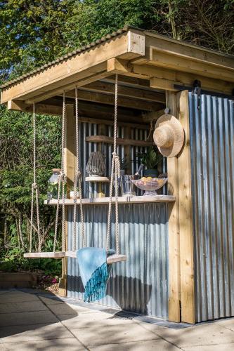 a wooden pergola with a table and a swing at Kionslieu Farm Cottages in Foxdale