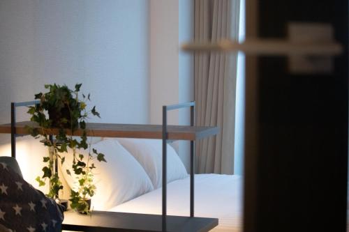 a bedroom with a bed with white sheets and a plant at Nagomi Gokoro Village Shin-Osaka in Osaka