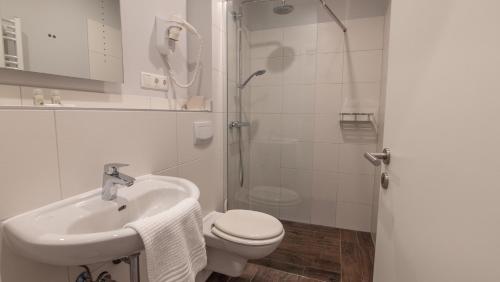 a bathroom with a toilet and a sink and a shower at Hotel-Restaurant Tüxen in Rendsburg